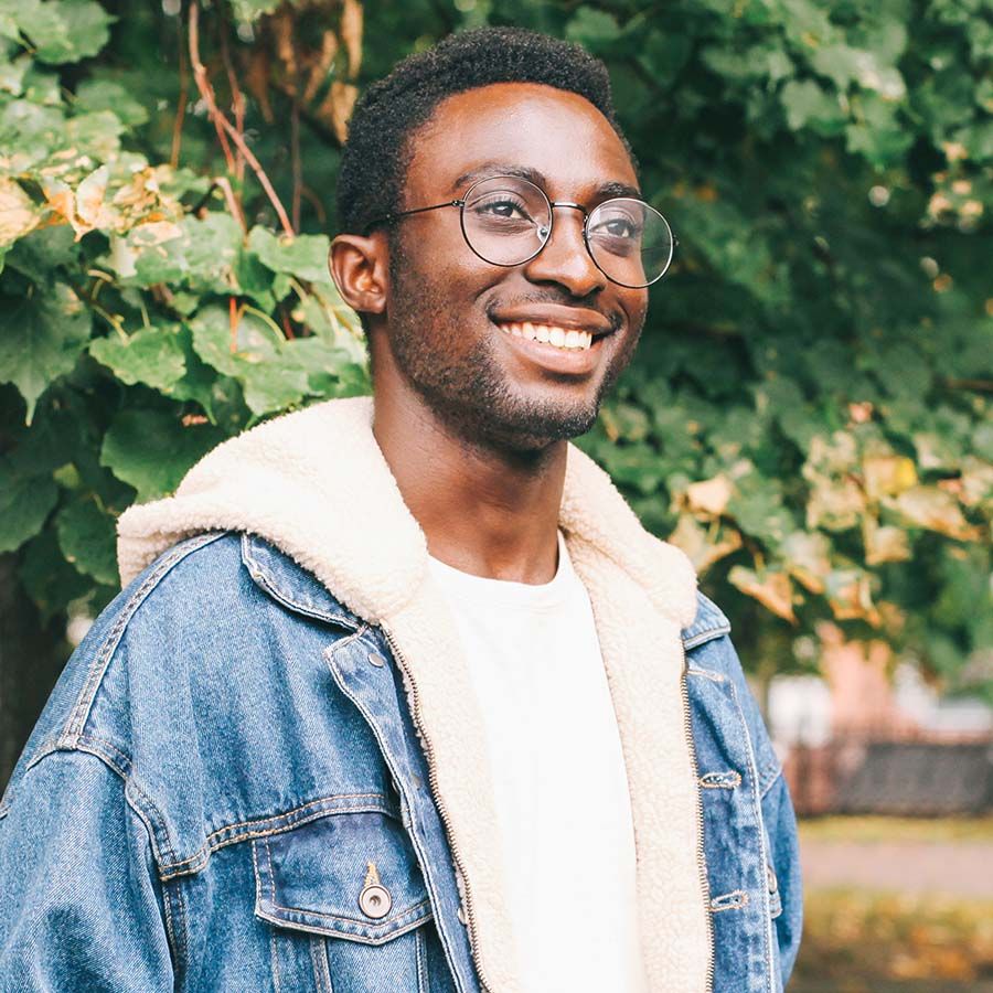 A man smiling outdoors in soft daylight.