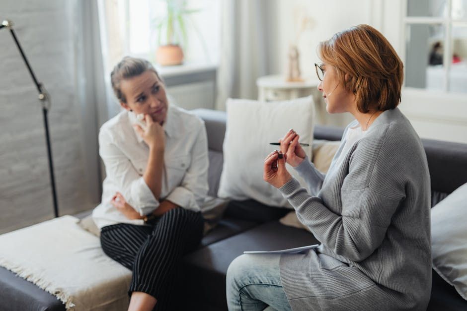 A clinician sitting with a patient in a calm therapy setting