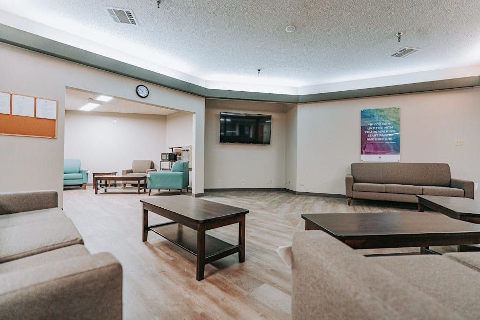 The day room at Hickory Grove Recovery in Morrilton with sofas, coffee tables and a wall-mounted TV