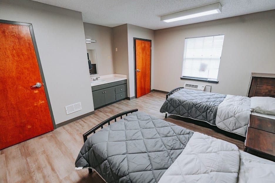 A two-bed resident room at Hickory Grove Recovery in Morrilton with a sink, a dresser and a window