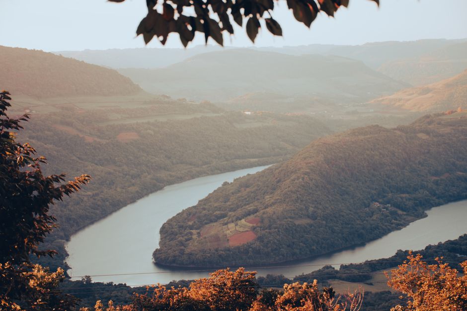 Aerial view of a meandering river through a lush green valley in autumn.