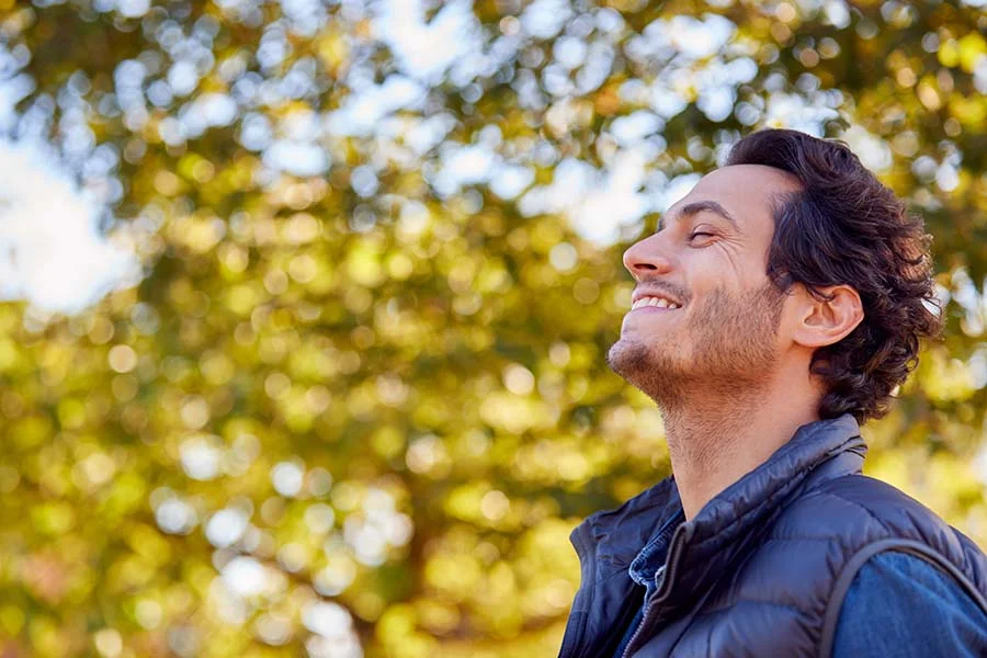 a man stands in a field with his eyes closed and face tilted up toward the sky