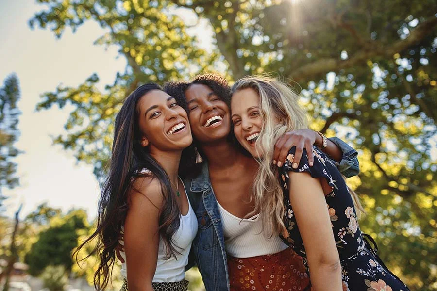 a group of girl friends hugs on the sidewalk