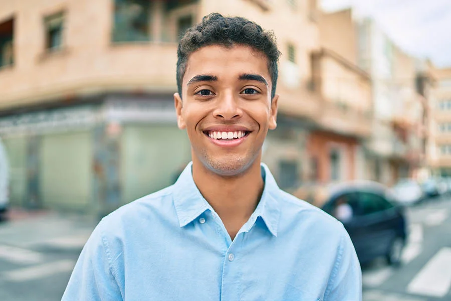 a smiling man stands at an intersection