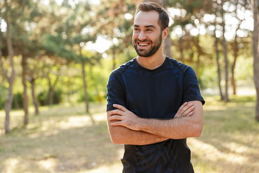 a man on a walk in a park stops and smiles at the camera