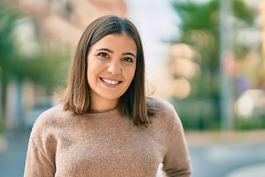 a woman in a gray sweater smiles at the camera