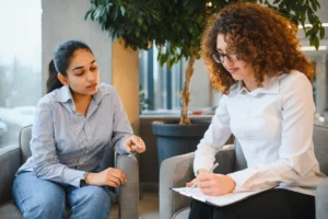 Two women sitting in chairs looking at clipboard