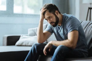 Man stressed on couch holding head