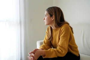 Woman sitting in room ruminating